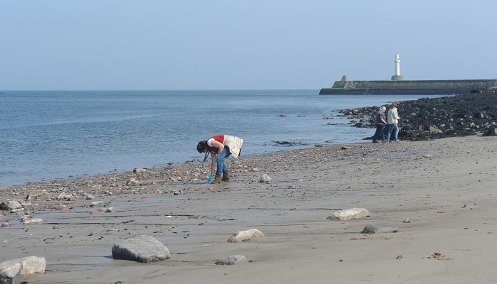Colleagues collecting litter on an Aberdeen beach. Crown copyright