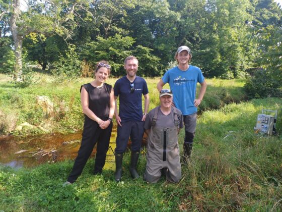 Cabinet Secretary Mairi Gougeon, left, standing next to three males with a forest backdrop.