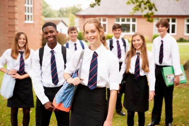 Group of school children in uniform standing outside looking at the camera
