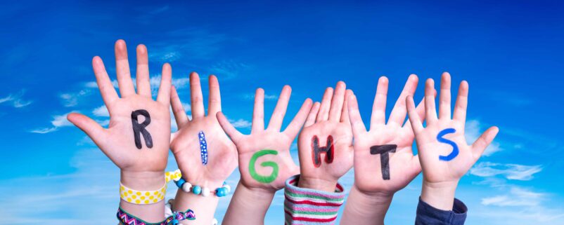 children's hands raised in front of the sky. On each hand is a letter spelling out "rights"