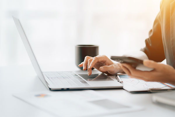 Image of person using laptop and mobile phone.